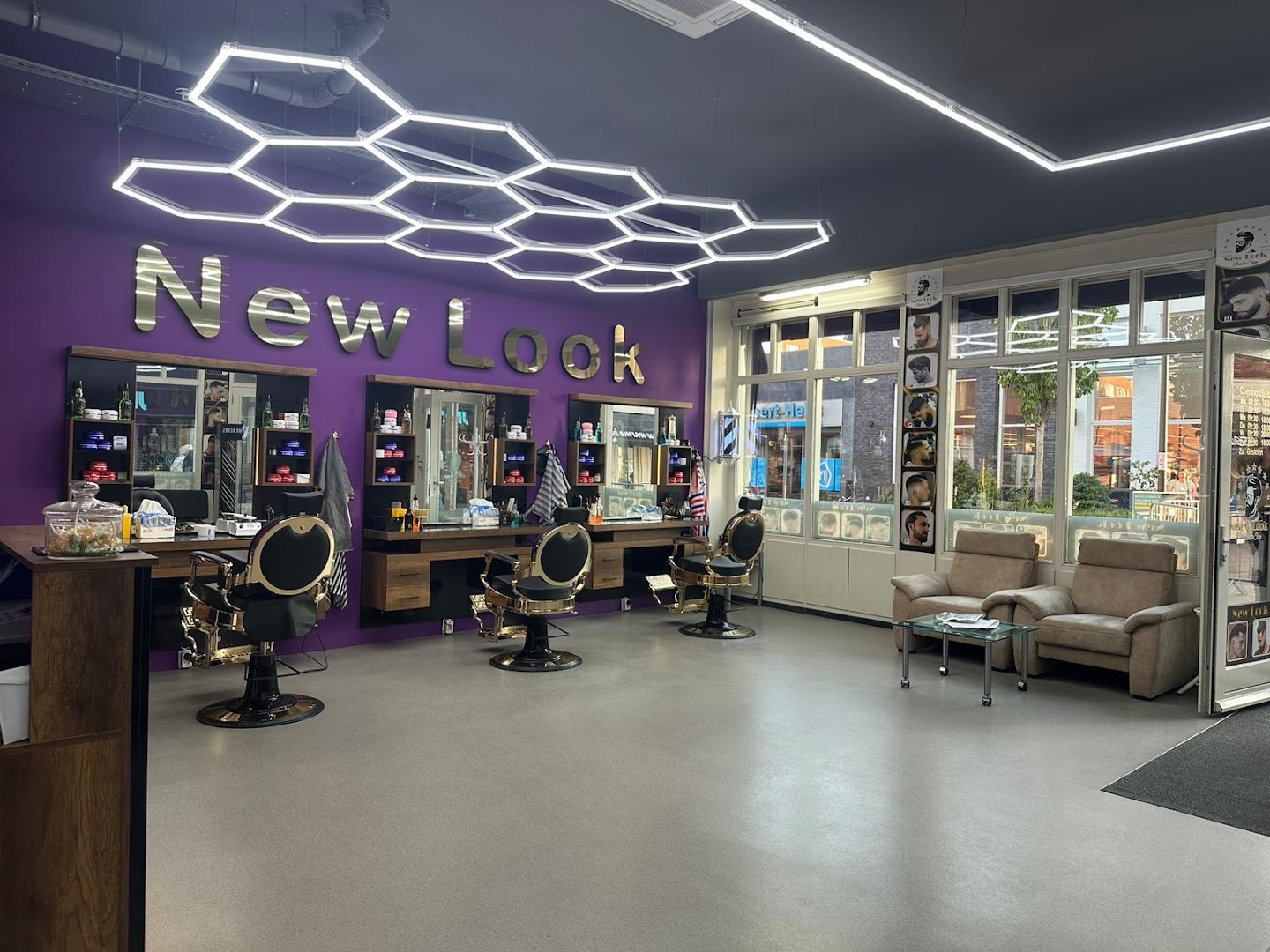Het interieur van New Look Barber Shop: paarse wanden, gouden barbierstoelen en hexagon-LED-verlichting